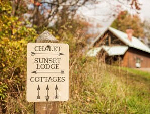 Ein Wegweiser zu einer Chalet-Pension, einem Abendstimmung-Logis und Hütten.