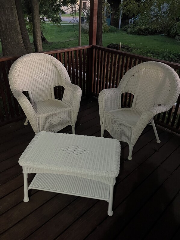 A covered outdoor seating area with two wicker chairs and a matching bench.