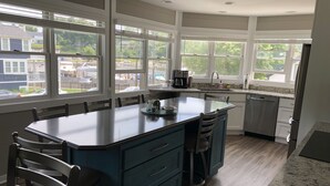 Una cocina moderna con una isla grande, armarios blancos y vistas al vecindario.