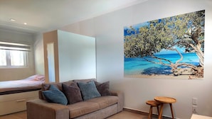A modern room with a sofa, a round table, and a painting of a beach scene. - Villa Valentina Aruba (Noord)