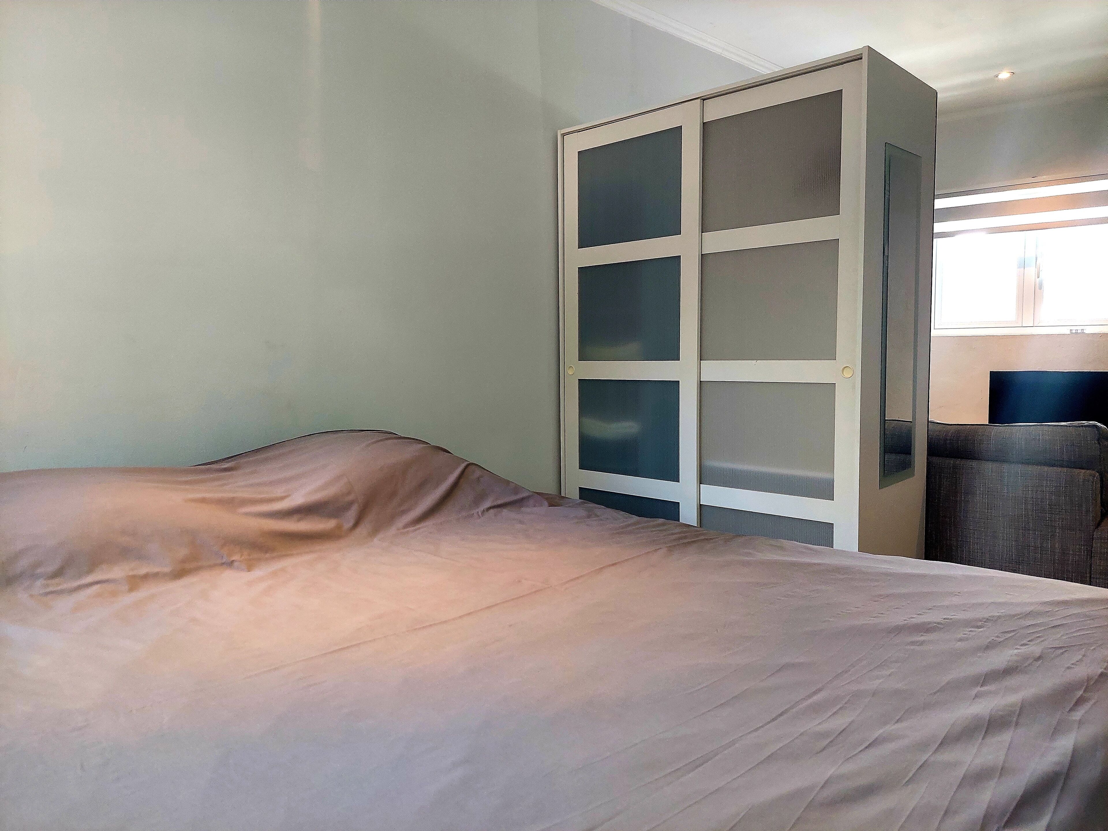 Een slaapkamer met een bed, een kledingkast en een televisie.