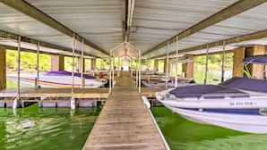 A covered boat dock with multiple moored boats, wooden walkways, and a central open space. - Pet-Friendly Cabin with Designated Boat Slip! (Greers Ferry)