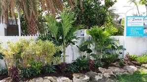 Un jardin avec différentes espèces de plantes et un panneau indiquant « Sunrise Beach Vacation Rentals and Homes ».