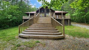 A wooden cabin with a staircase leading to a deck, surrounded by trees. - Cozy Cabin at Little River Canyon (Fort Payne)