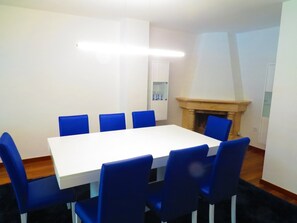 A conference room with a white table and blue chairs, a fireplace, and a cabinet with wine glasses. - Private Heated Swimming Pool (Porto)