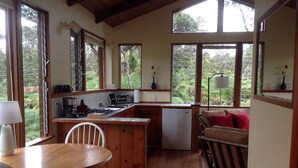 A compact kitchen with wooden cabinets, a small refrigerator, and a dining area with a table and chairs.