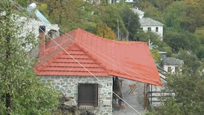 A stone house with a red tiled roof, a wooden door, and a small porch area. - Small Detached House Of 60 M2 Situated In Koukourava, Makrinitsa In Pelion Mt. (Μακρινίτσα, Κουκουράβα)