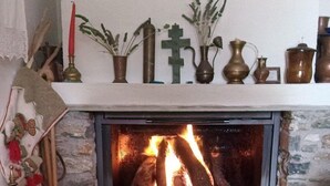 A fireplace with a stone surround, a mantel decorated with various items, and a wooden floor. - Small Detached House Of 60 M2 Situated In Koukourava, Makrinitsa In Pelion Mt. (Μακρινίτσα, Κουκουράβα)