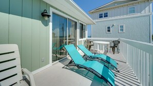 A balcony with a white railing, a glass door, and a table with chairs.