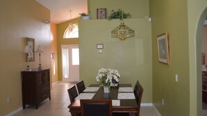 Un coin repas avec une table dressée pour quatre personnes, des chaises, un lustre et un buffet orné de lampes.