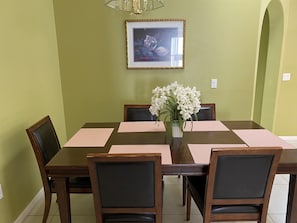 A dining table with six chairs, a vase with white flowers, and a framed picture on the wall. - Luxury Villa - Pool, LCD TVs , Free Internet On Disney's Doorstep !! (Kissimmee)