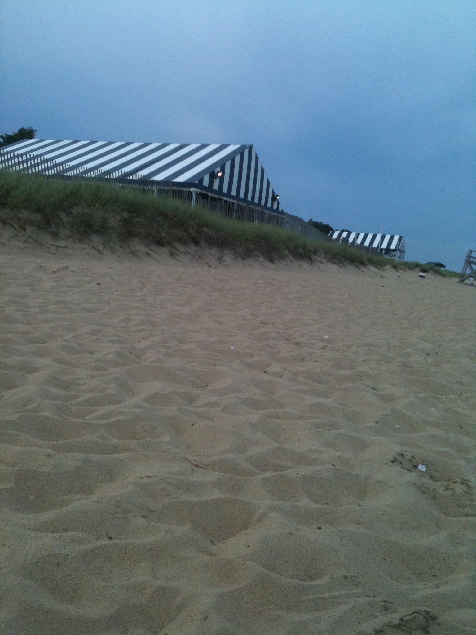 Een strand met een gebouw met strepen op de achtergrond.