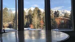 Une pièce dotée d’une grande fenêtre donnant sur une cha îne de montagnes et un chalet en bois.