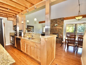 A modern kitchen with granite countertops, wooden cabinets, a large island, and a stone accent wall. - Gorgeous Condo in Top Corner Location- Great Views & Private Deck with Barbecue (Wilson)