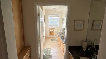 A narrow hallway leading to a bathroom with a sink, mirror, and window.