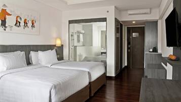 Une chambre d’hôtel avec deux lits, un grand miroir, une télévision et un plancher en bois.