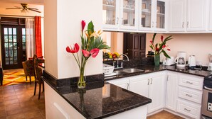 Eine moderne Küche mit weißen Schränken, Granit Arbeitsplatten und einem Essbereich mit Stuhl und Tisch.