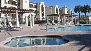 A pool area with lounge chairs and a pergola. - Luxurious, peaceful beachfront condo minutes from St Augustine and Daytona Beach (Beverly Beach)