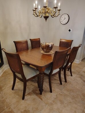 A dining table with six chairs, a chandelier, and a wall clock. - Luxurious, peaceful beachfront condo minutes from St Augustine and Daytona Beach (Beverly Beach)