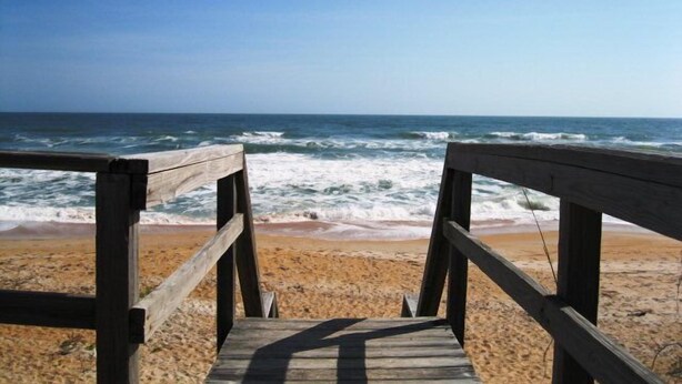A wooden boardwalk leading to a sandy beach with the ocean in the background. - Luxurious, peaceful beachfront condo minutes from St Augustine and Daytona Beach (Beverly Beach)