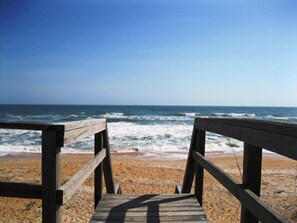 A wooden boardwalk leading to a sandy beach with the ocean in the background. - Luxurious, peaceful beachfront condo minutes from St Augustine and Daytona Beach (Beverly Beach)