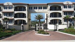 A multi-story hotel with a central archway, balconies, and a paved driveway. - Luxurious, peaceful beachfront condo minutes from St Augustine and Daytona Beach (Beverly Beach)