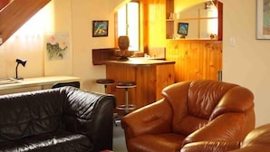 En hyggelig stue med en bar i træ, lædersofaer og et spisebord.