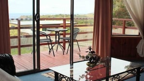 Et værelse med en stor skydedør, der fører ud til en terrasse med et bord og stole.