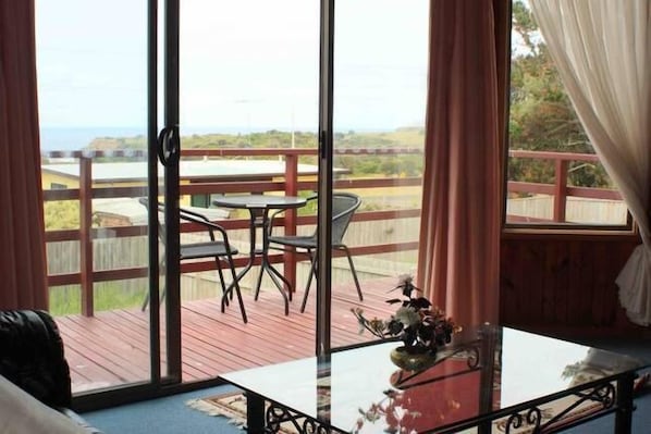 A room with a large sliding glass door leading to an outdoor deck with a table and chairs.