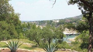 A landscaped garden with agave plants, a river, and a distant view of a town. - 4/2 by Marina, Near Wineries, Grill, WiFi, View (Spicewood)