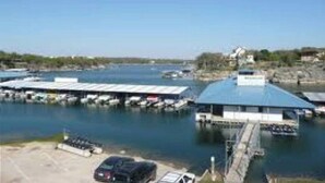 A marina with boats docked, a covered parking area, and a building with a blue roof. - 4/2 by Marina, Near Wineries, Grill, WiFi, View (Spicewood)