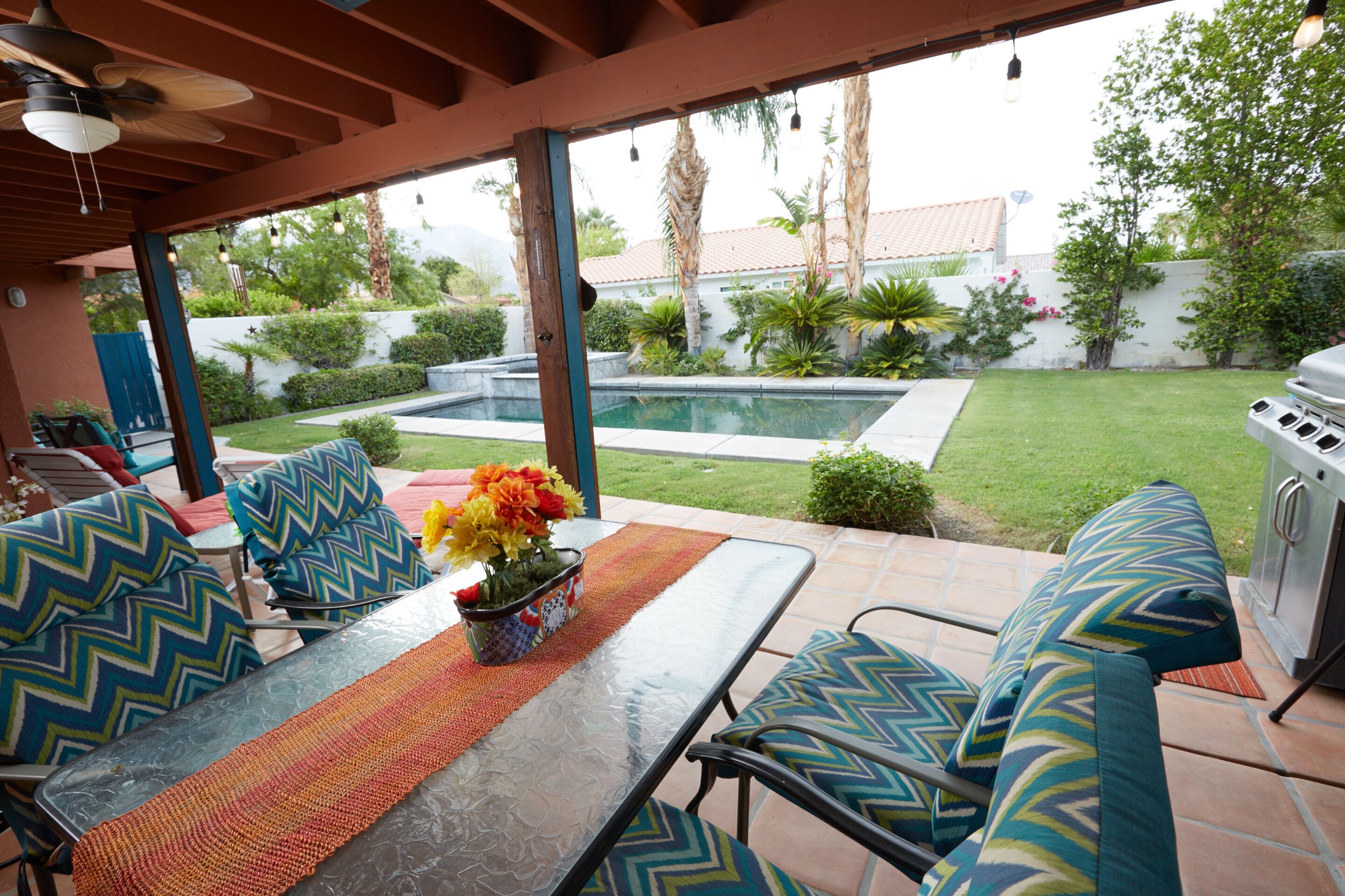 Une terrasse extérieure avec une table, des chaises et un barbecue.