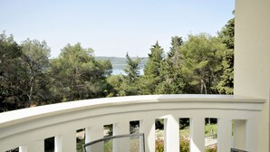 Un balcon doté d’une balustrade blanche, offrant une vue sur un lac et une forêt dense.
