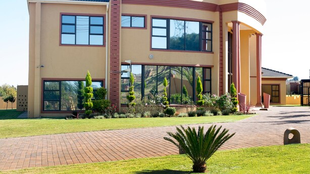A modern two-story building with large windows, a brick pathway, and well-maintained landscaping.