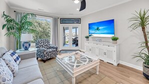 A modern living room with a sofa, armchair, coffee table, TV, and potted plants. - Marina view Condo in Wild Dunes Resort, Isle of Palms, SC (Isle of Palms)