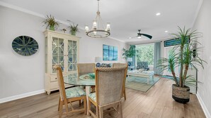 A dining area with a glass table, wicker chairs, a white cabinet, and a chandelier. - Marina view Condo in Wild Dunes Resort, Isle of Palms, SC (Isle of Palms)