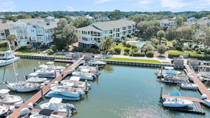 A marina with multiple boats docked, surrounded by residential buildings with large windows and balconies. - Marina view Condo in Wild Dunes Resort, Isle of Palms, SC (Isle of Palms)