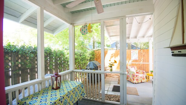A covered porch with a table and chairs, a ceiling fan, and a view of the backyard.