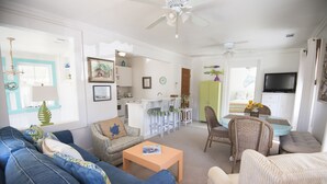 A living room with a sofa, chairs, a coffee table, a dining table, and a television.