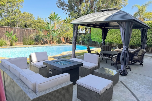 Cushioned outdoor seating areas around the fire pit and inside the gazebo