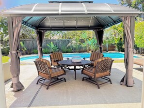 Ein überdachter Patio-Bereich mit Pool, ausgestattet mit Korbstühlen und einem runden Tisch.