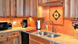 A kitchen with wooden cabinets, a granite countertop, a double sink, a coffee maker, and a microwave.