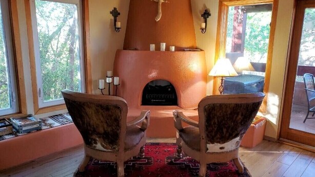 A cozy room with a fireplace, two armchairs, and a rug.