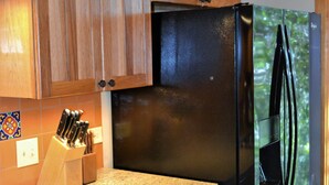 A kitchen with wooden cabinets, a granite countertop, and a black refrigerator.