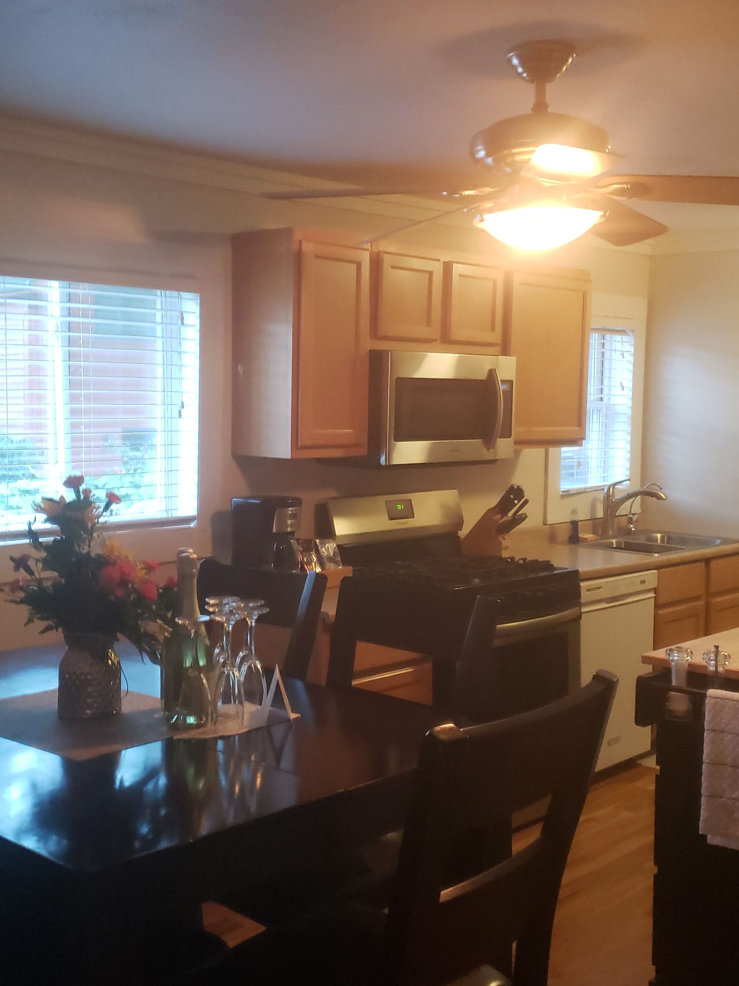 A kitchen with wooden cabinets, a microwave, a stove, and a dining table with chairs.