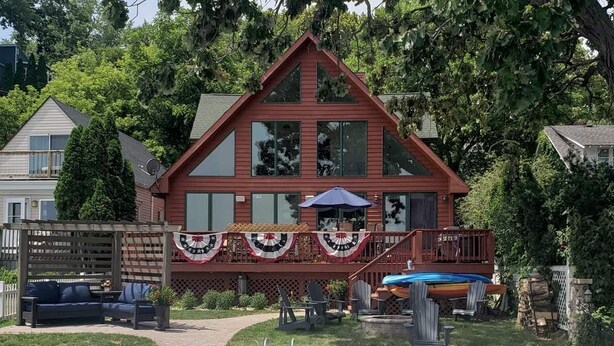 A two-story house with a deck, outdoor seating, and a small pool.