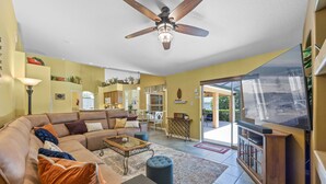 A living room with a brown leather sofa, a glass coffee table, and a television. - VERY CLEAN & SPACIOUS! Pool, Game Room, BBQ, 2 King Masters--Close to Disney! (Clermont)