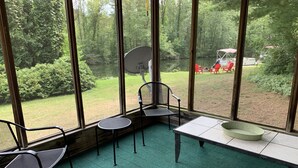 Een kamer met grote ramen, een groen tapijt, een tafel en twee stoelen.