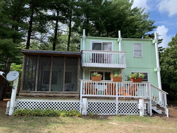 A two-story building with a balcony, a covered porch, and a fenced yard.