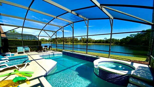 Piscina al aire libre techada con sillas de descanso y un jacuzzi, con vistas a un lago.